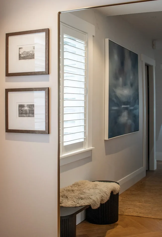 Mirror, timber stool, and framed artwork in hallway nook