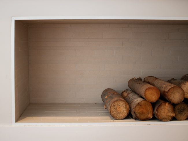 Built-in wood storage cubby beside fireplace
