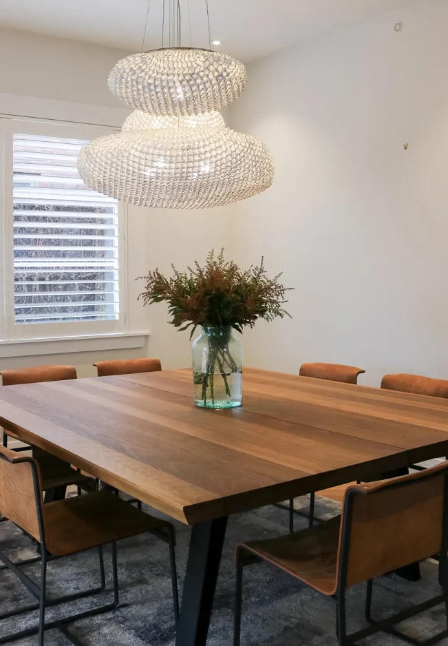 Chandelier above timber dining table with leather chairs