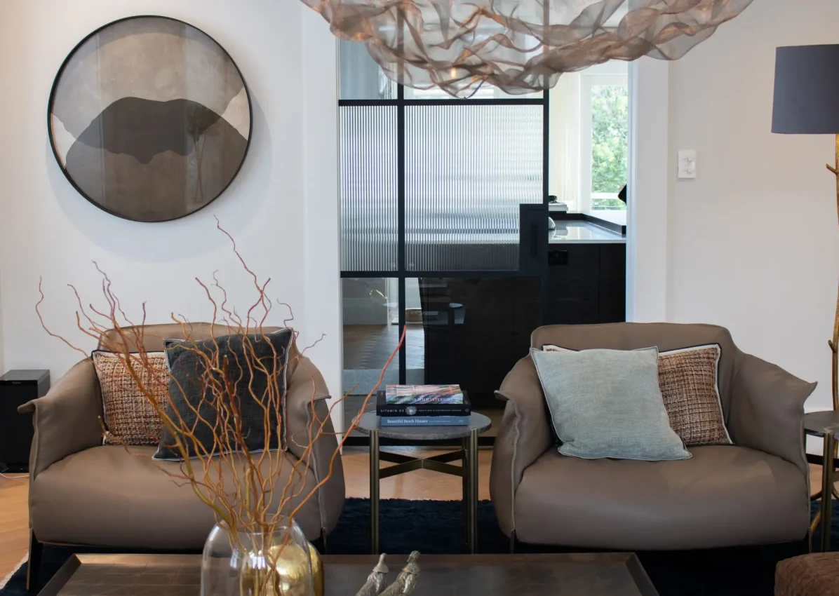 Pair of leather chairs in lounge with view to kitchen