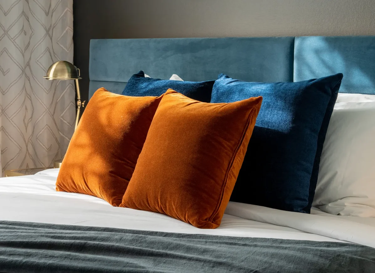 TRYP Wellington hotel bed with orange and blue cushions and blue headboard.